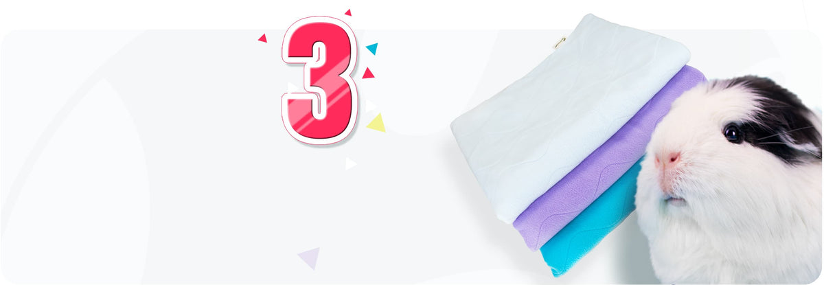 Três mantas de polar Guineapet dobradas, em branco, lilás e turquesa, ao lado de um porquinho-da-índia: forros absorventes para gaiola